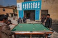 Chinese man playing billiards at courtyard at old village in the center, enjoy activity after work. Yunnan, China